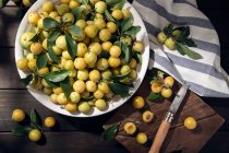 Fruta de mirabela de ameixa amarela fresca na tigela na mesa de madeira — Fotografia de Stock