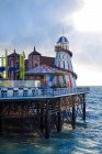 Colorful attractions of amusement park on pier near waving sea against cloudy sky in evening in Brighton, England — Stock Photo