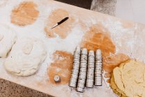 De haut petit couteau et ensemble de tasses placées sur la table farinée dans la boulangerie — Photo de stock