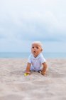 Vue frontale d'un bébé blond sur la plage — Photo de stock