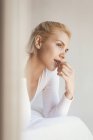 Young woman with blond hair and in bodysuit looking away at home — Stock Photo