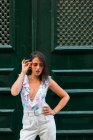 Moderne schöne Frau im trendigen Outfit, die neben der Tür des Gebäudes steht und auf die malerische Straße hinunterblickt — Stockfoto