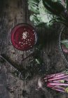 Copa de licuado de remolacha orgánica deliciosa con semillas de sésamo en la mesa de madera con verduras crudas y llave vintage - foto de stock