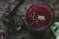 Glass of organic delicious beetroot smoothie with sesame seeds on wooden table with vintage key — Stock Photo