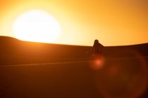 Silhouette viaggiatore irriconoscibile scattare foto di dune mentre in piedi sulla sabbia in un deserto incredibile — Foto stock
