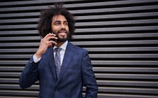 Афроамериканський чоловік розмовляє по телефону біля стіни — стокове фото