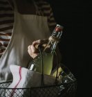 Крупный план женской руки, несущей корзину с бутылкой сиропа бузины, полотенцем и стеклом — стоковое фото