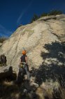 Arrampicatore con casco arancione sta fissando la cima della montagna che sta per scalare — Foto stock
