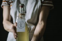 Mittelteil der Frau mit einer Flasche Holunderblumenwein mit Liebesetikett — Stockfoto