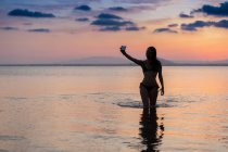 Mulher sedutora tomando selfie na água — Fotografia de Stock