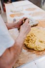 Homem de colheita em t-shirt branca colocando massa fresca em copos enquanto faz pastelaria na cozinha da padaria — Fotografia de Stock