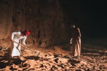 Árabes homens cavando areia perto de penhasco — Fotografia de Stock