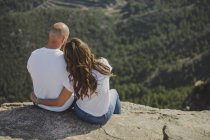 Joyeux couple assis sur une falaise — Photo de stock