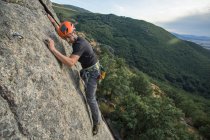 Человек карабкается по скале на природе с альпинистским снаряжением — стоковое фото