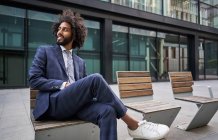 Felice imprenditore afro-americano sorridente mentre seduto fuori — Foto stock