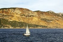 White sailboat in sea and beautiful rocks — Stock Photo