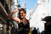 Verspielte Frau im langen Kleid hält eine Fotokamera in der Hand, während sie durch die Sommerstraße der Stadt läuft — Stockfoto