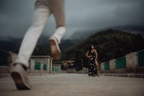 Man running to date with beautiful woman standing in long dress on stone bridge — Fotografia de Stock