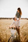 Flirter Mann und Frau auf geschmücktem Fahrrad im gleißenden Sonnenlicht auf goldenem Roggenfeld im Sommer — Stockfoto