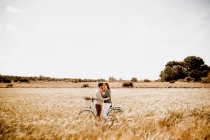 Amantes sinceros posando de bicicleta no campo de centeio — Fotografia de Stock