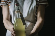 Close-up of woman holding bottle of elderflower drink with Made with love label — Stock Photo