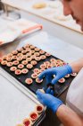 Unbekannter Konditor verziert rosa Teig auf Tablett bei Bäckereiarbeit — Stockfoto