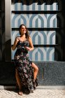 Мирная роскошная женщина в модном наряде и блестящих солнцезащитных очках, стоящая рядом с экзотической стеной на живописной улице — стоковое фото