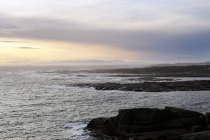 Massi lisci sulla costa vuota con onde marine sotto il cielo scuro della sera in Norvegia — Foto stock