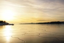 Ampio fiume mozzafiato con scioglimento e screpolatura strato di ghiaccio liscio sotto maestoso cielo colorato tramonto — Foto stock