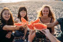 Eine Gruppe von Freunden am Strand sammelt ihre Wassermelonenstücke — Stockfoto