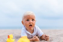 Portrait of baby boy playing with rubber ducks on the beach — Stock Photo