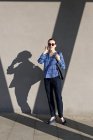 Attraktive Managerin in blau kariertem Hemd und Sonnenbrille, die mit dem Smartphone spricht und wegschaut — Stockfoto