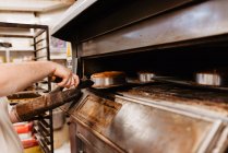 Чоловік заглядає всередину професійної печі під час роботи в пекарні — стокове фото