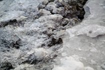 Derretendo gelo e neve no topo da superfície rochosa com seixos à luz do dia — Fotografia de Stock