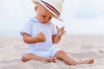 Vista frontal de un bebé en la playa con un sombrero - foto de stock