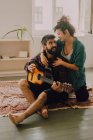 Ніжна весела пара в повсякденному вбранні грає на гітарі вдома — стокове фото