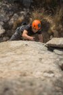 Зверху людина піднімається на скелю в природі з обладнанням для скелелазіння — стокове фото