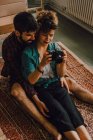 De cima vista de hipster homem e mulher casal usando câmera de fotos sentado descalço no chão do apartamento — Fotografia de Stock