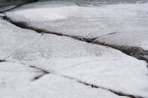 Close-up of processed rock surface with cracks and scratches covered with snow — Stock Photo