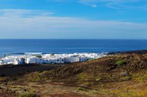 Paisagem incrível de casas brancas colocadas na costa remota de mar azul calmo sob céu infinito em Lanzarote, Ilhas Canárias, Espanha — Fotografia de Stock