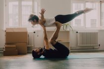 Vue latérale du couple athlétique exerçant et équilibrant ensemble sur le sol dans un appartement moderne — Photo de stock
