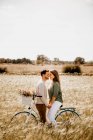 Amantes sinceros posando en bicicleta en el campo de centeno - foto de stock