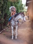 Sério menino no autêntico indiana pena chapéu equitação cavalo no parque — Fotografia de Stock