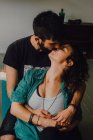 Ласковая пара в повседневных нарядах целуется и обнимается во время отдыха в современной квартире — стоковое фото