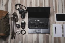 Dall'alto set di attrezzature fotografiche professionali disposte vicino al laptop su una superficie di legno — Foto stock