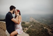 Sensual pareja besándose mientras descansa en mesa de observación rural - foto de stock