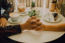 Крупним планом красива пара тримає руки, сидячи за столом в кафе — стокове фото