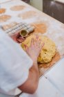 Erntehelfer in weißem T-Shirt steckt frischen Teig in Tassen, während er in der Küche der Bäckerei Teig zubereitet — Stockfoto