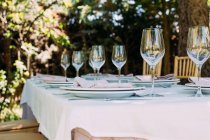 Outdoor rustic celebration table with cutlery and glasses — Stock Photo