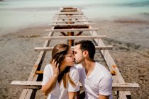 Щасливі коханці сидять на зруйнованому причалі на березі моря — стокове фото